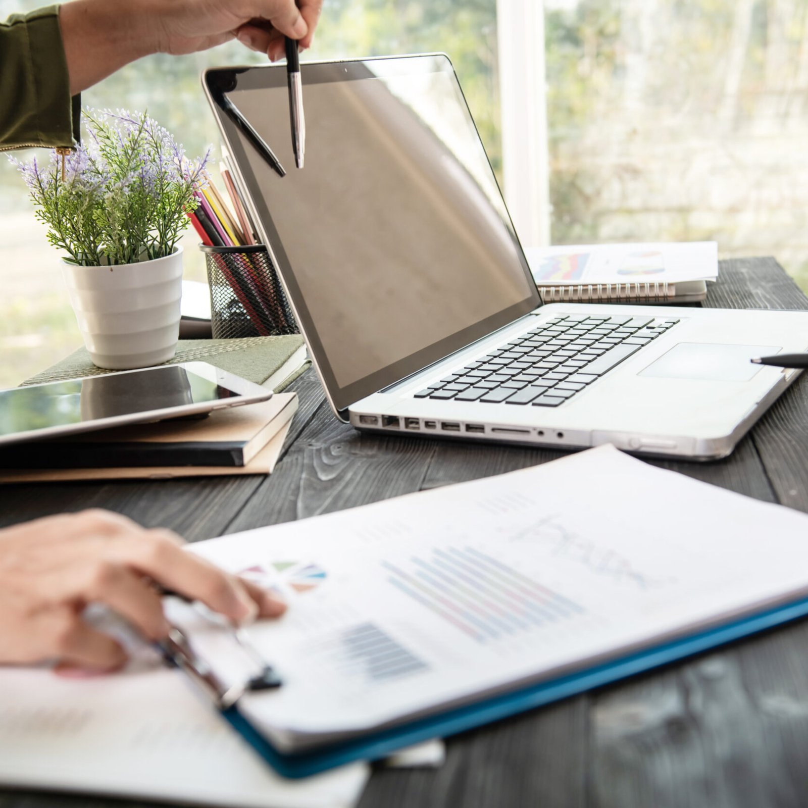 business woman hands using laptop computer placed on messy office desktop. teamwork with business people analysis cost graph on desk at meeting room.